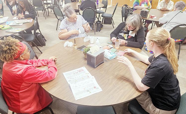Nicole Wright/Staff Correspondent Beading jewelry during the Learning Leisure Skills session at the annual Multicultural Women’s Development Conference, sponsored by One Dozen Who Care Inc. last weekend at Hinton Life Center in Hayesville. From left are Glynette Scott, Patricia Hall, Emory Prescott and Hannah Larson.