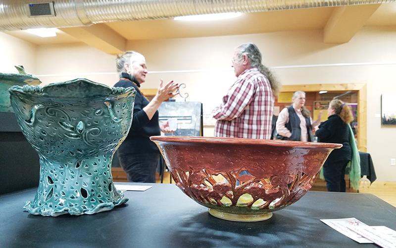 The “Fashioned in the Clay” show displays a variety of items, from practical to decorative, including Lisa Proper’s intricate fruit and centerpiece bowls. In the background, Elo-ly Bailey, David Vowell, Kathy Ross and Proper hold conversations during the exhibit’s opening.